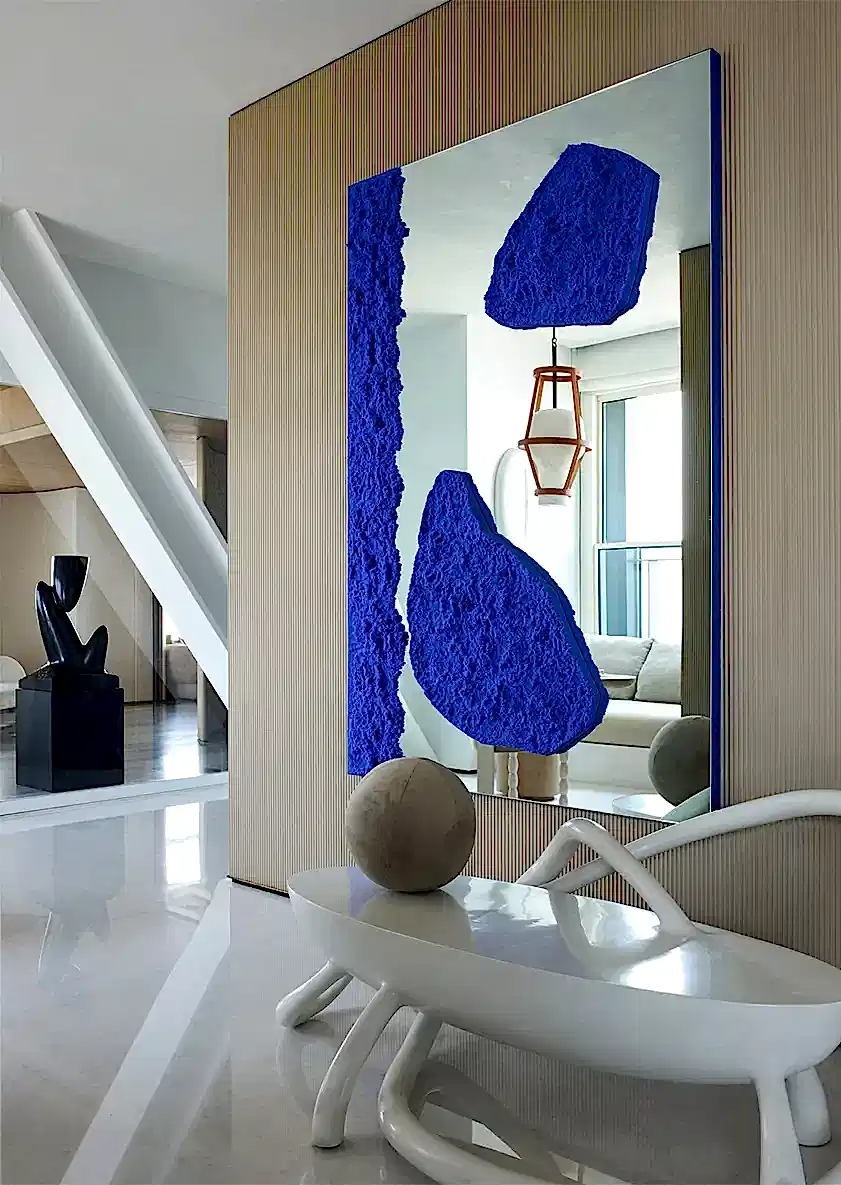 Curating complimenting delicate wall hung mirror artwork with contrasting blue details that compliments contemporary wall paneling to home entrance hallway